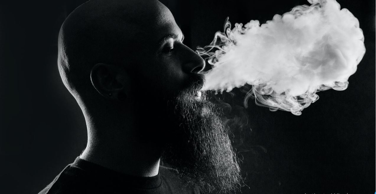 a beard man is vaping smoke